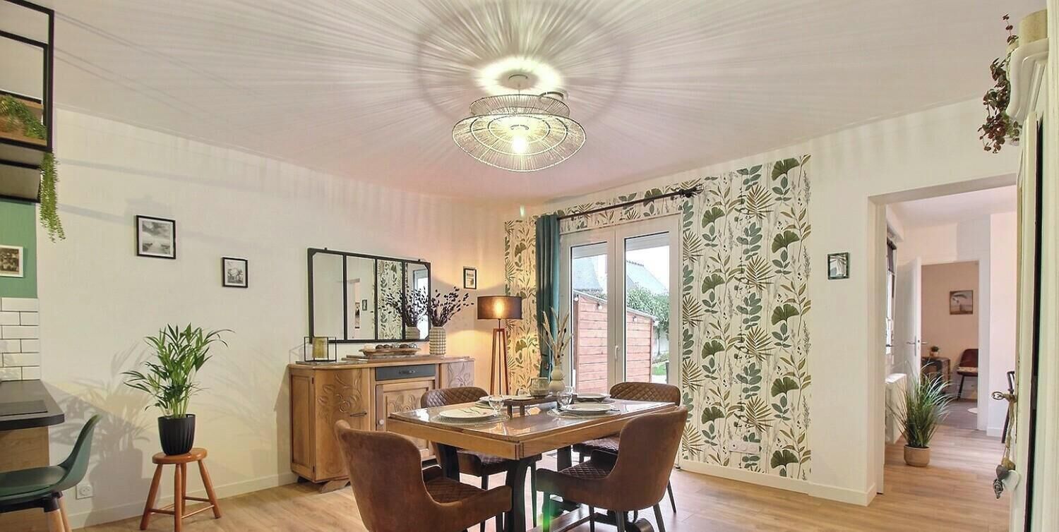 Ein Essbereich mit Holztisch, Stühlen, einer Chandelier und Blick ins Freie.
