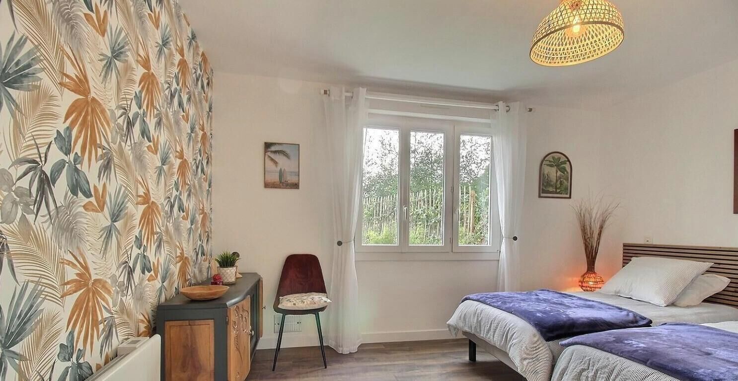 Un dormitorio con cama, escritorio, silla, ventana y lámpara colgante.