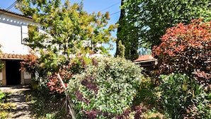 A garden with various plants and trees, a building with a tiled roof, and a clear blue sky. - 1 bedroom beautiful home in Verzeille (Verzeille)