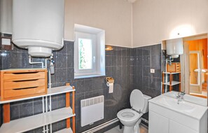 Une salle de bain équipée de toilettes, d’un lavabo, d’une fenêtre et d’un radiateur.