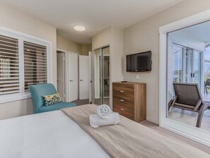 A bedroom with a bed, a chair, a dresser, a television, and a sliding glass door to a balcony. - The Pool Resort Kingscliff - One Bedroom (4316) with ocean view - Holiday Management Co. (Tweed)