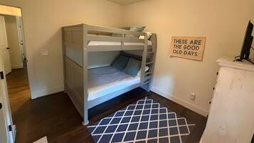 A bunk bed room with a ceiling fan, a sign on the wall, and a patterned rug.