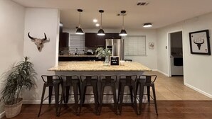 Una cocina con una isla central, taburetes de bar, luces colgantes y una decoración con cráneo de toro.