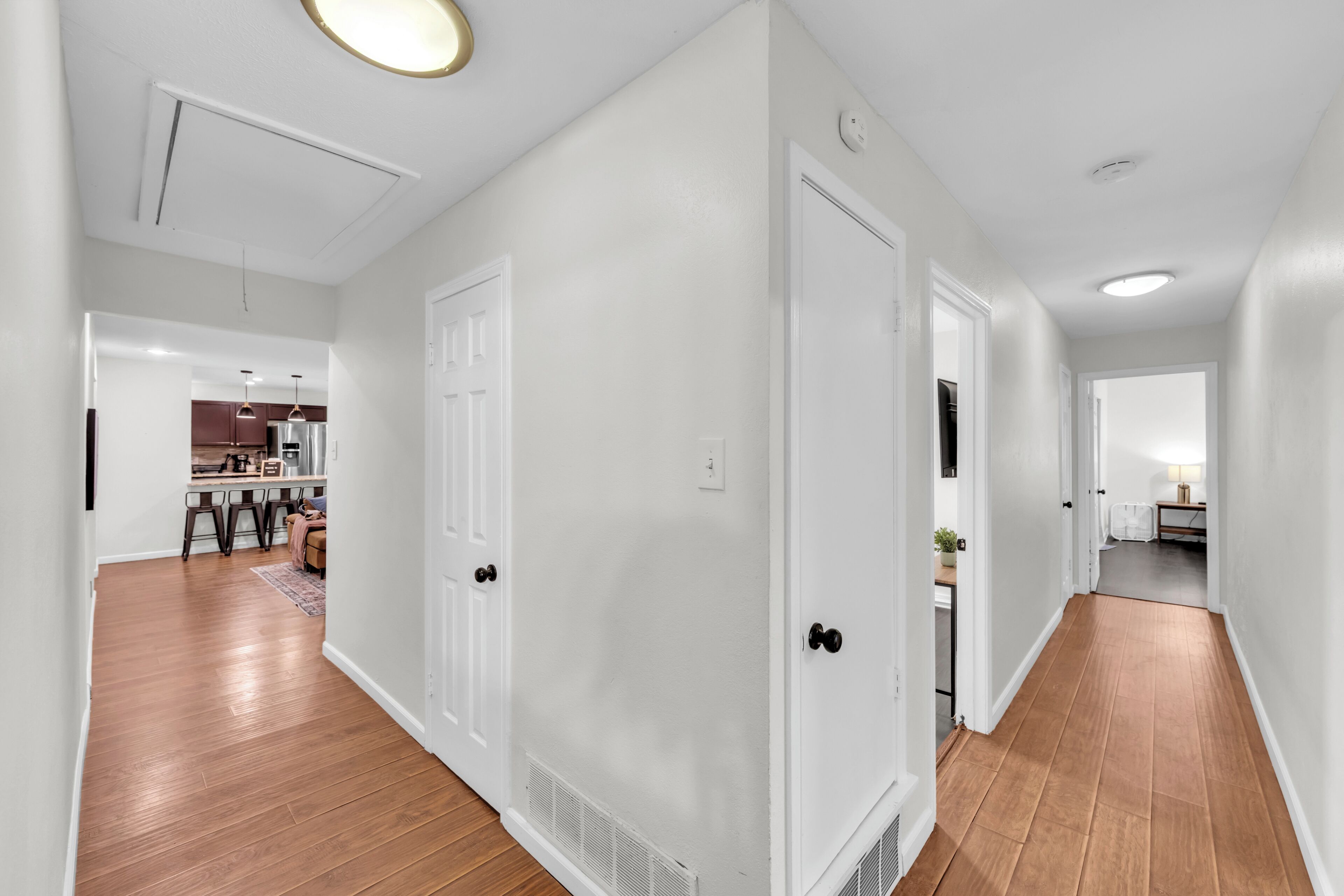 A hallway with wooden flooring, white walls, and doors leading to different rooms.