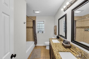 Une salle de bain comprenant une baignoire, des toilettes, un meuble-lavabo avec un miroir et un espace douche.