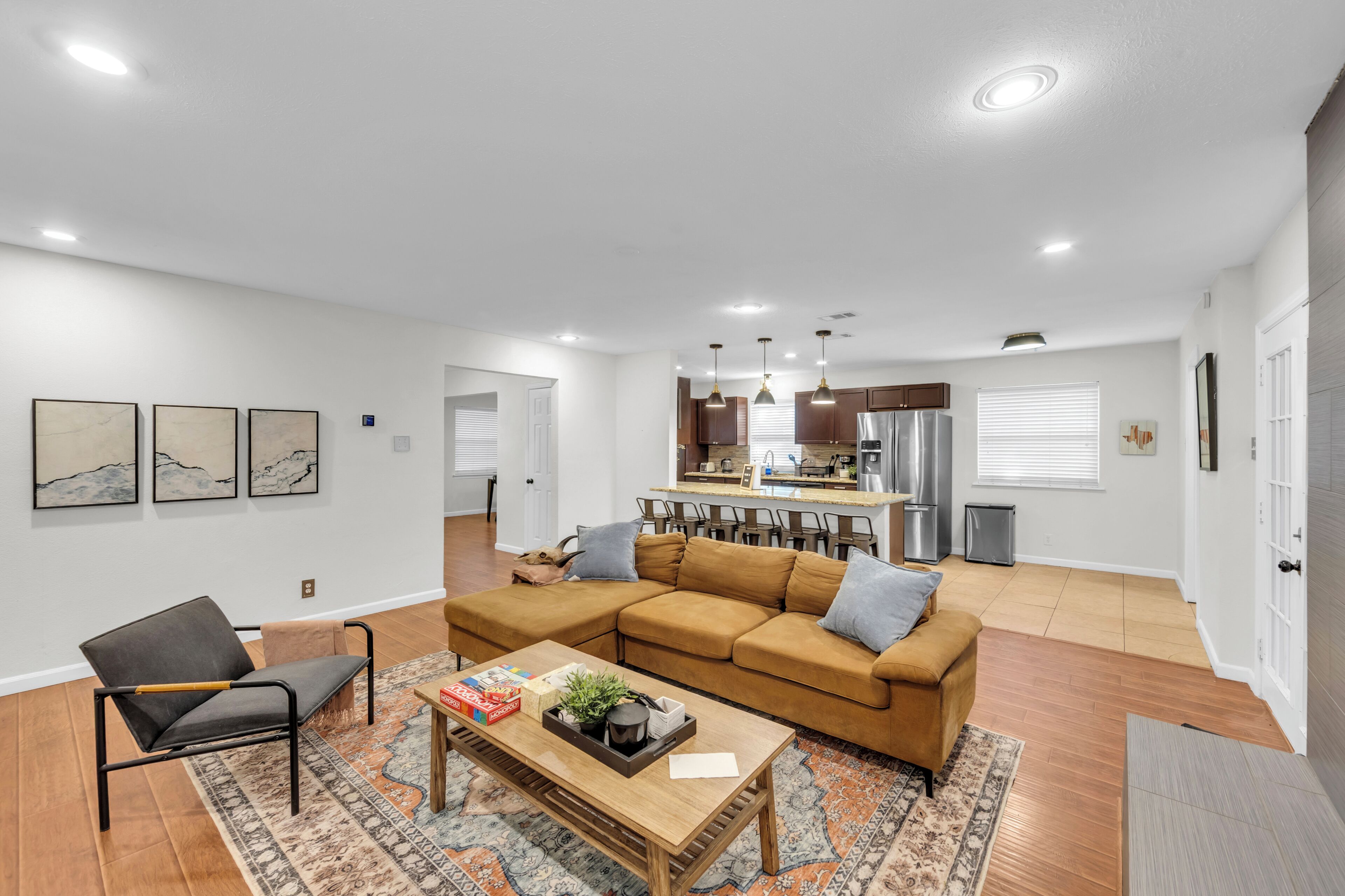 Una sala de estar moderna con un sofá modular, una mesa de centro y una cocina al fondo.