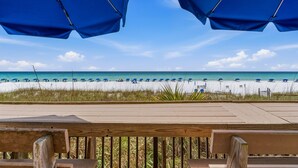 Blick auf einen Strand mit Sonnenschirmen und einer Holzterrasse.