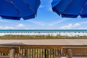 Blick auf einen Strand mit Sonnenschirmen und einer Holzterrasse.