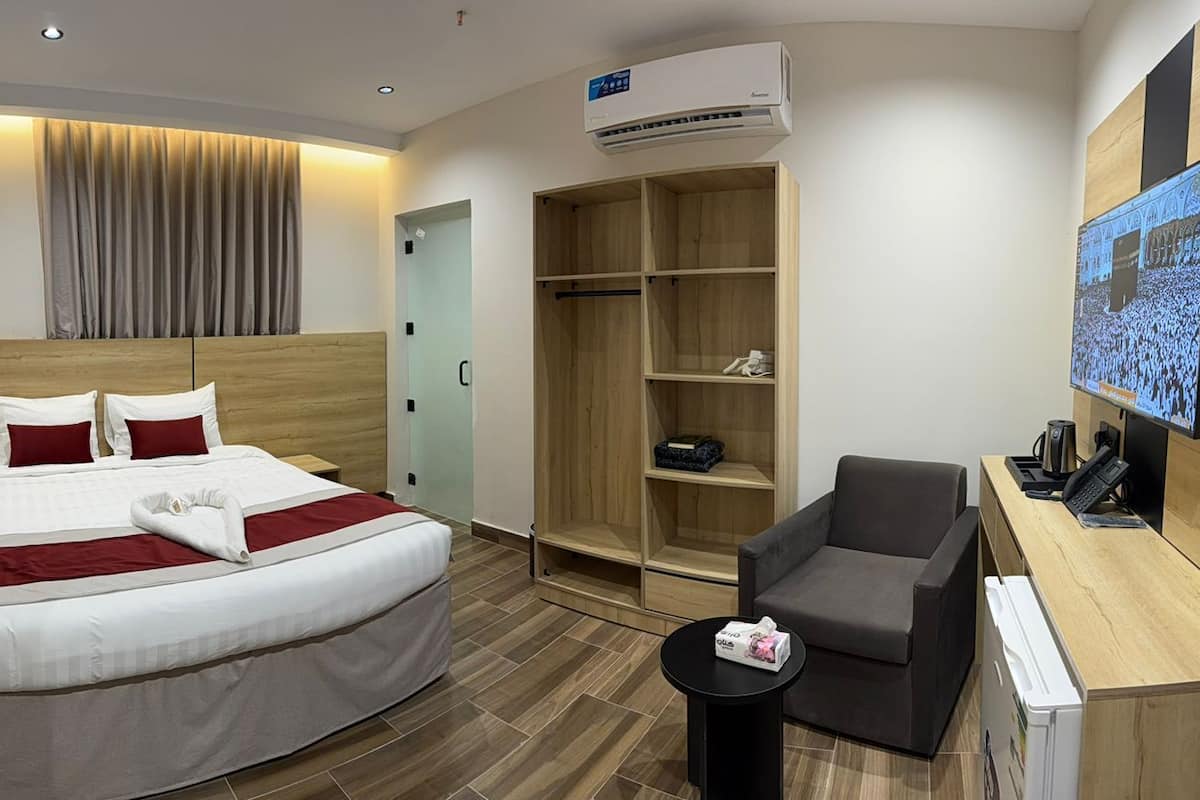 Une chambre d’hôtel comprenant un lit, un bureau, une chaise, une armoire et un téléviseur.