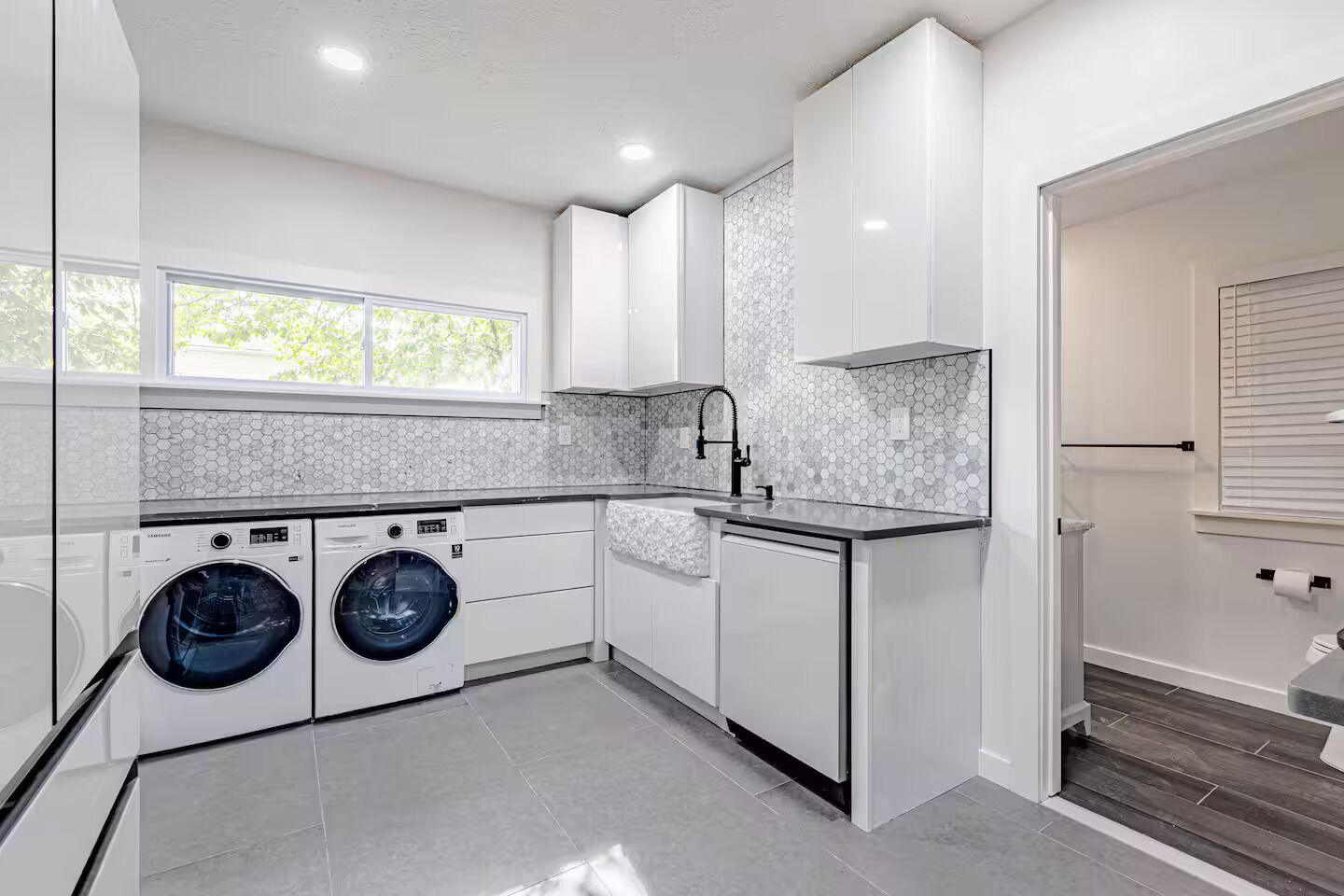 A modern kitchen with built-in appliances, a large window, and a view of the outdoors.