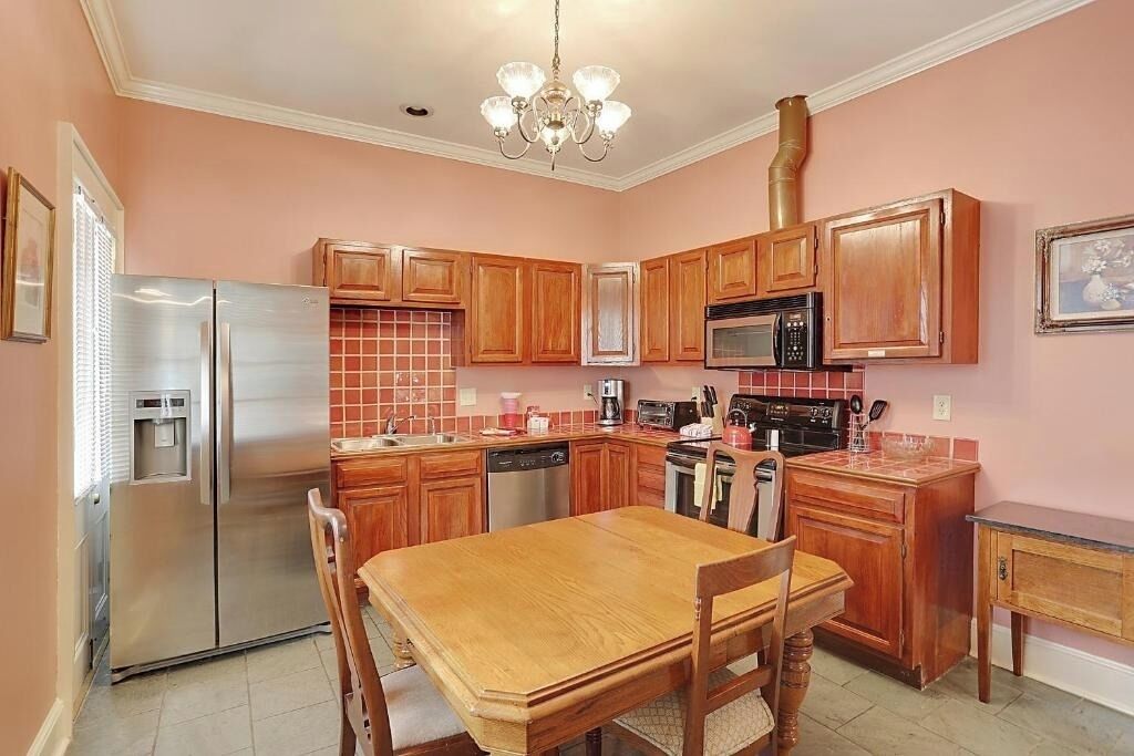 A kitchen with wooden cabinets, stainless steel appliances, and a dining table with chairs.