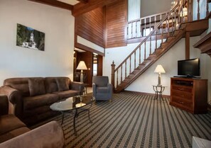 A living room with a sofa, armchairs, a coffee table, a TV, and a staircase. - Cozy 1-bedroom condo with AC in terrific Steamboat Springs (Steamboat Springs)