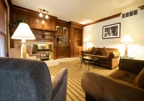A living room with a fireplace, wooden cabinets, and two lamps. - Cozy 1-bedroom condo with AC in terrific Steamboat Springs (Steamboat Springs)