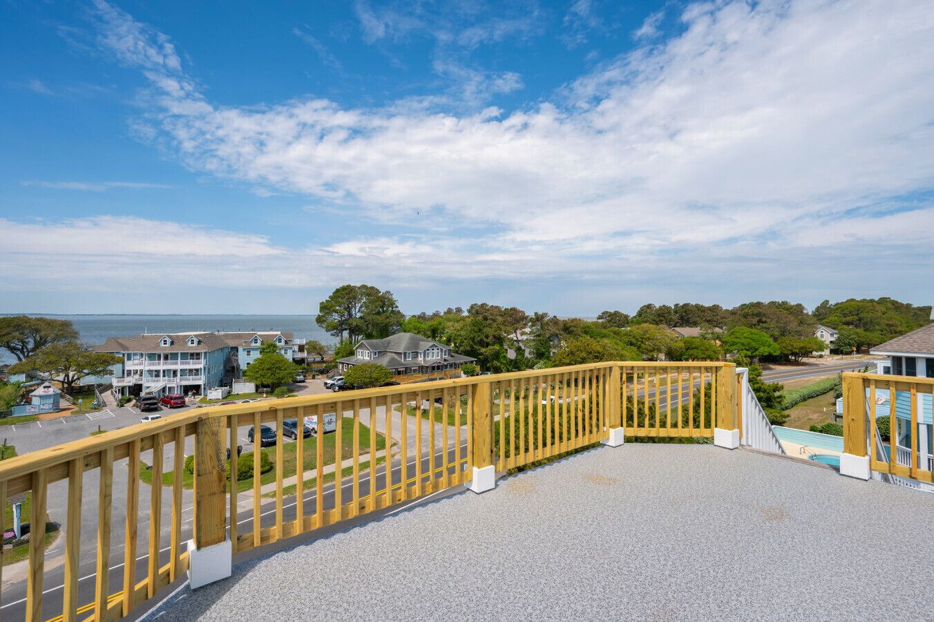 Un quartier résidentiel en bord de mer, doté d’une terrasse en bois, d’une piscine et de maisons offrant une vue sur l’océan.