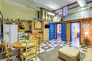 A compact kitchen with wooden cabinets, a dining table, and a checkered floor.