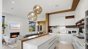 A modern kitchen with white cabinets, a central island, and pendant lighting. - Luxury Dunbar Home — Rooftop, Putting Green & Park (Vancouver)