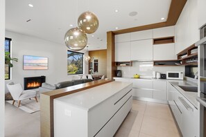 A modern kitchen with white cabinets, a central island, and pendant lighting. - Luxury Dunbar Home — Rooftop, Putting Green & Park (Vancouver)