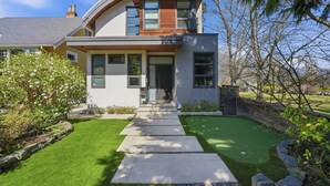 A modern two-story house with a curved roof, a front entrance, and a well-maintained lawn. - Luxury Dunbar Home — Rooftop, Putting Green & Park (Vancouver)
