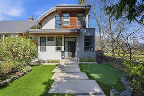 A modern two-story house with a curved roof, a front entrance, and a well-maintained lawn. - Luxury Dunbar Home — Rooftop, Putting Green & Park (Vancouver)