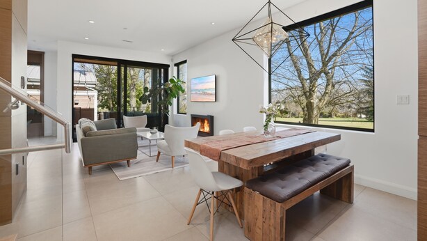 A modern living room with a wooden dining table, white sofas, and a fireplace. - Luxury Dunbar Home — Rooftop, Putting Green & Park (Vancouver)