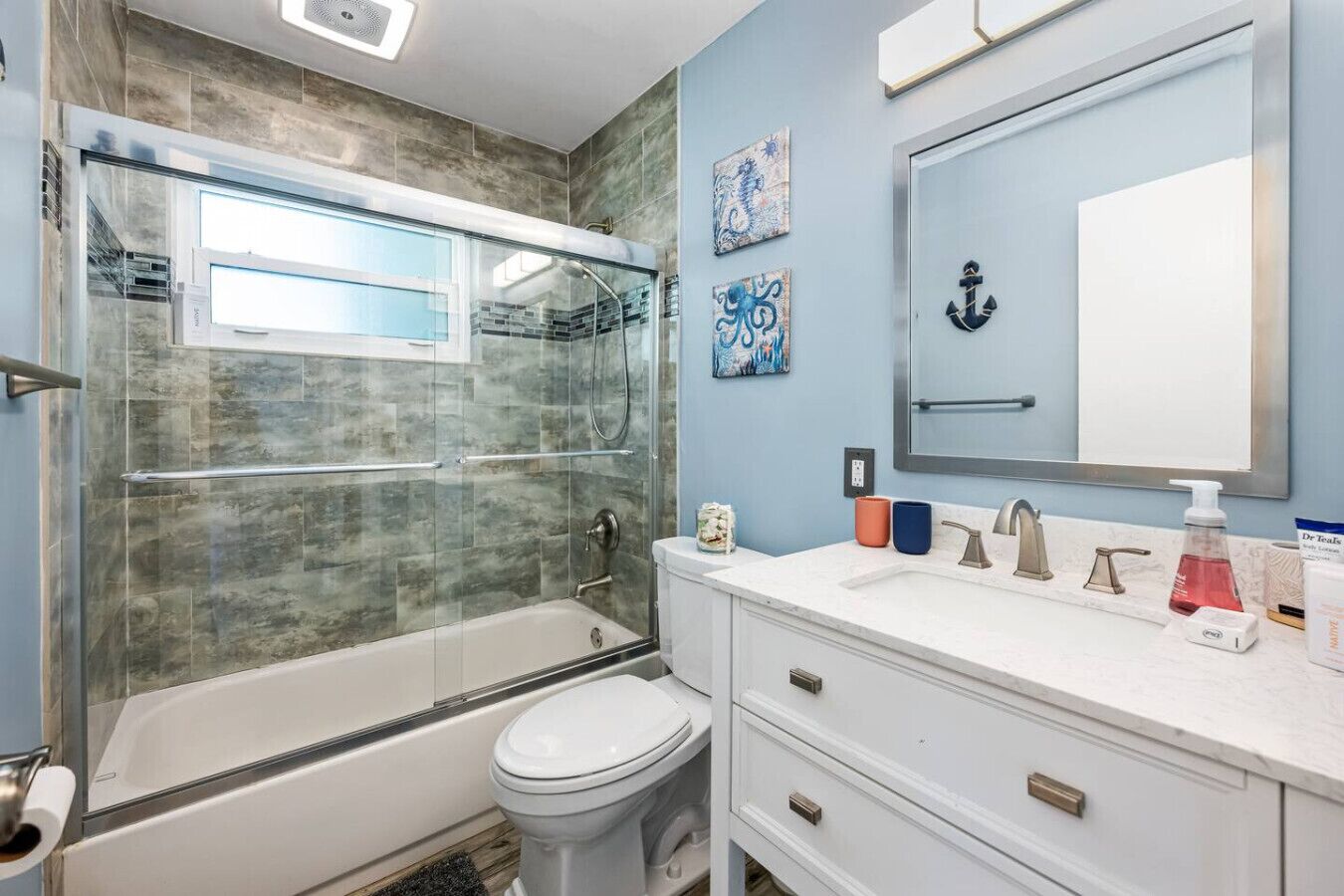 A modern bathroom with a glass-enclosed shower, a white toilet, and a vanity with a mirror and sink.