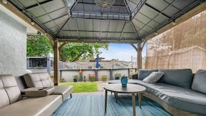 An outdoor patio with a covered seating area, a round table, and potted plants. - Family 3BR w/ Pool | Game Room I Walk to WaterPark (Margate)