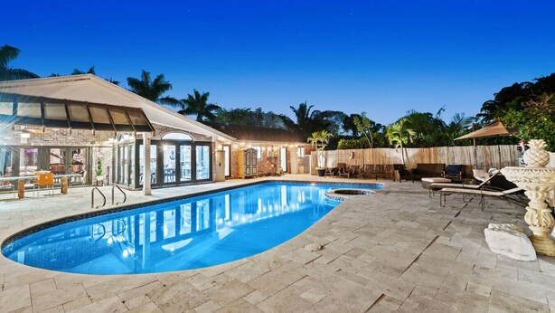 A swimming pool with a sunken section, a covered patio area, and a brick wall.
