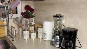 A kitchen with a sink, a coffee maker, a blender, and various kitchen utensils and containers.