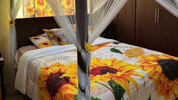 A bed with a floral bedspread, a canopy, and a nightstand with a lamp.