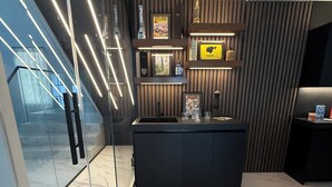 Una cucina moderna con pavimento in marmo, un'isola centrale e una parete in legno decorata con quadri e una bottiglia di liquore.