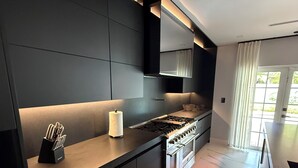 Una cucina moderna con mobili scuri, un piano cottura in acciaio inossidabile e forno integrato.
