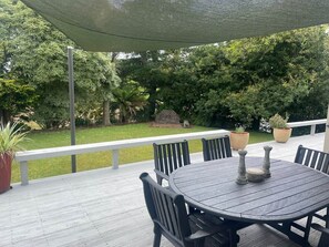 Eine Terrasse im Freien mit einem runden Tisch und Stühlen, umgeben von Topfpflanzen und einem Holzboden.