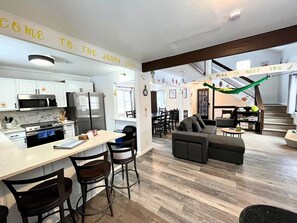 Eine moderne Küche mit weißen Schränken, einem Edelstahlkühlschrank und einem Essbereich mit einer Couch und Stühlen.