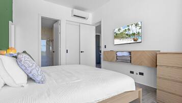 Un dormitorio con cama, armario, un cuadro y la puerta del baño.