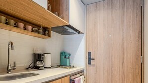 A modern kitchen with wooden cabinets, a built-in shelf with mugs, a coffee maker, and a hanging towel. - NOK Modern Studio in Chapinero (Bogotá)