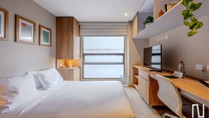 A modern hotel room with a bed, desk, TV, and large windows. - NOK Modern Studio in Chapinero (Bogotá)