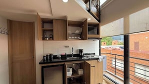 A compact kitchen with wooden cabinets, a black countertop, and a built-in refrigerator. - NOK Beautiful Apartment in Chico (Bogotá)