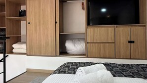 A modern bedroom with a large bed, a wardrobe with multiple compartments, and a television. - NOK Beautiful Apartment in Chico (Bogotá)