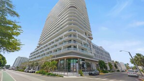 Un hotel alto y moderno con fachada curva, varios balcones y una entrada destacada.