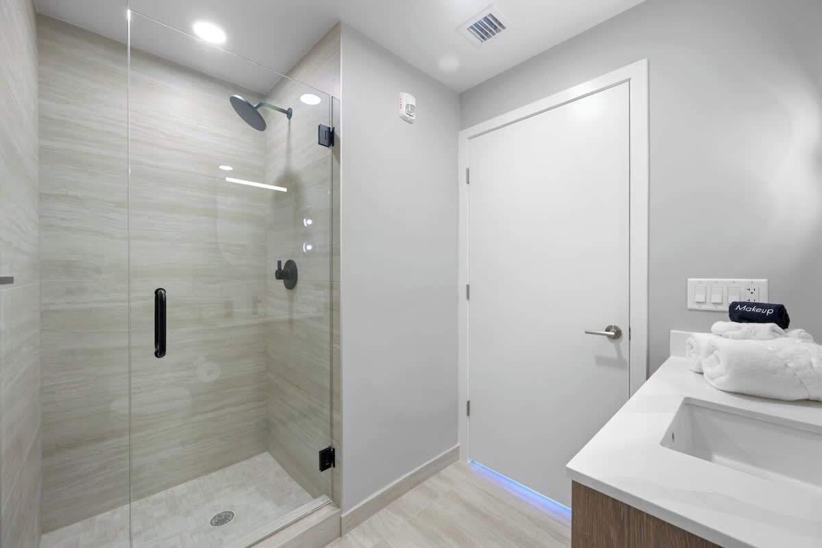 A modern bathroom with a glass-enclosed shower, a white sink, and a towel rack.