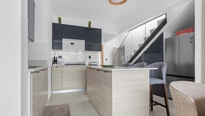 Eine moderne Küche mit einer zentralen Kochinsel, integrierten Geräten und einer Treppe zu einer oberen Ebene.