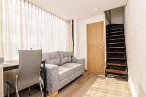 Ein Zimmer mit einem grauen Sofa, einer Holztür und einer Treppe.