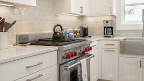 Una cucina moderna con mobili bianchi, elettrodomestici in acciaio inossidabile e una finestra che offre luce naturale.