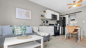 A modern living room with a sofa, coffee table, and a dining area with a chair and table. - NOK Amazing 1BR Apartment Jardines 3, Punta Cana (Punta Cana)