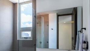 A modern bathroom with a glass shower enclosure, a toilet, and a vanity with a mirror. - NOK Fantastic 3BR in Usaquén (Bogotá)