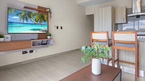 A modern kitchen with wooden cabinets, a built-in stove, and a large island with seating. - NOK Modern 1BR Apartment With Terrace in Vistacana (Punta Cana)