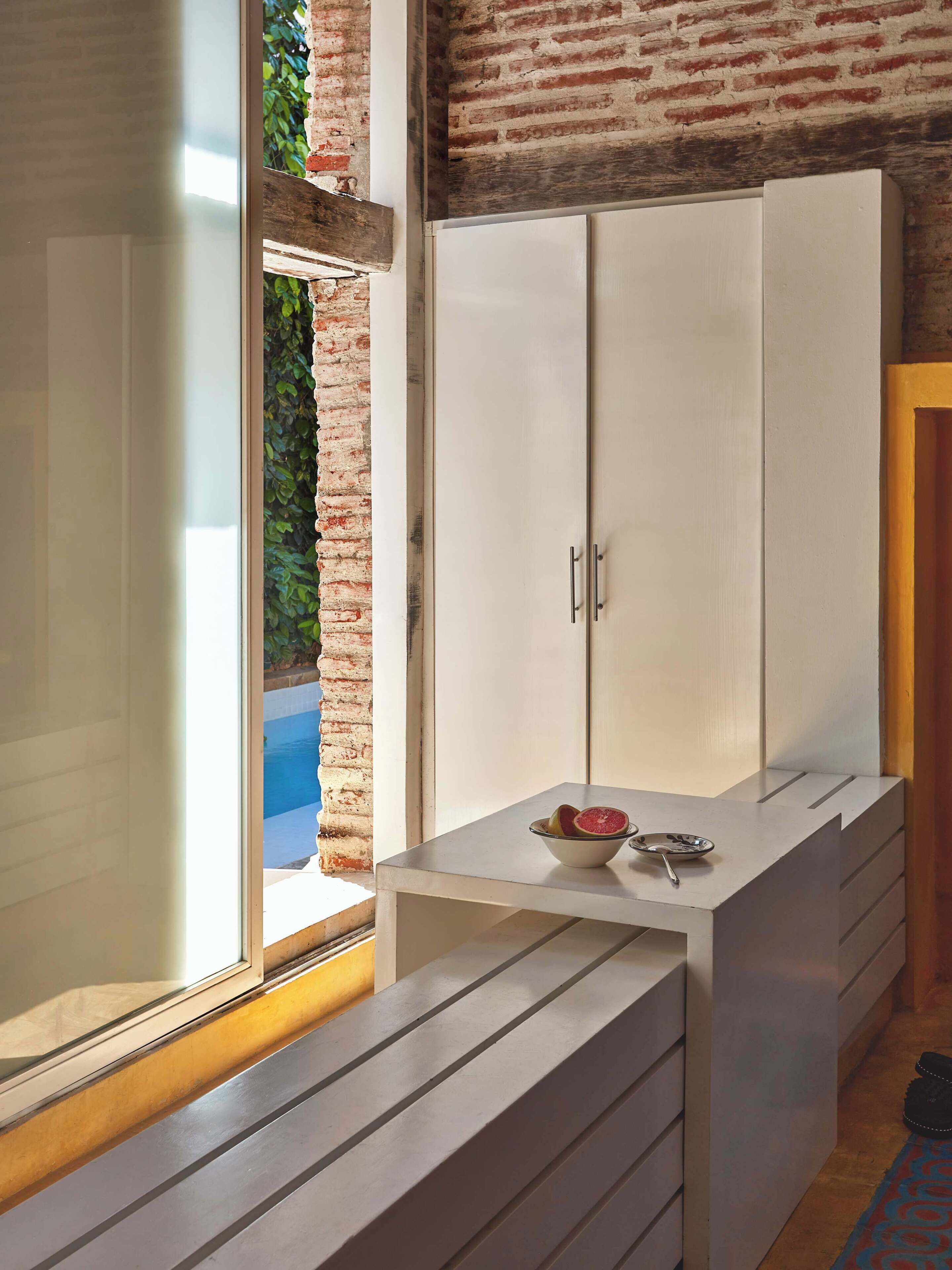 A room with a sliding glass door leading to a pool, a white wardrobe, and a small table with a bowl and spoon.