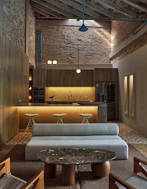 A modern kitchen with a central island, bar stools, a sofa, and a marble table. - NOK Luxury Colonial Villa 6BR With Pool, Staff & Breakfast at Getsemani (Cartagena)