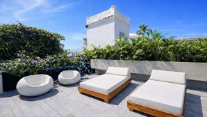 A rooftop terrace with three lounge chairs, a round seating area, and a white building in the background. - NOK Luxury Colonial Villa 6BR With Pool, Staff & Breakfast at Getsemani (Cartagena)