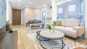 A modern living room with a sofa, round coffee table, and a dining area with a table and chairs. - NOK Designer 2BR in Usaquén (Bogotá)